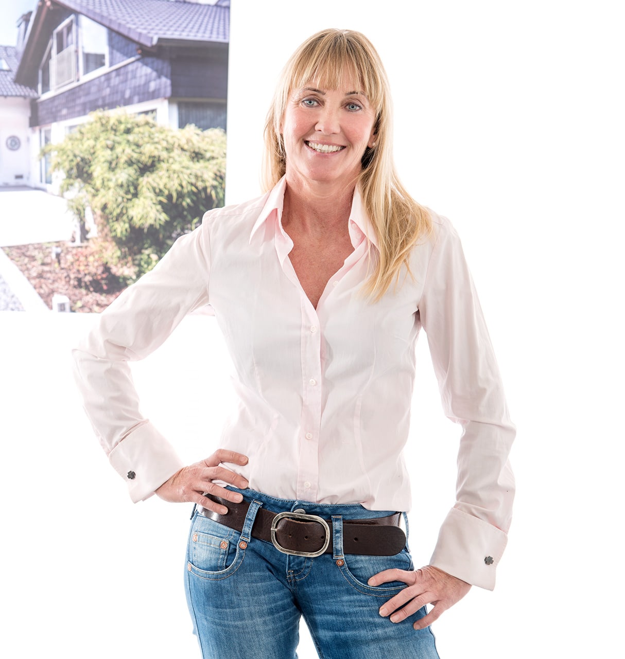 Frau in weißem Hemd und Jeans mit einem Poster eines Hauses im Hintergrund, verbunden mit Bautenschutz Bogumil GmbH.