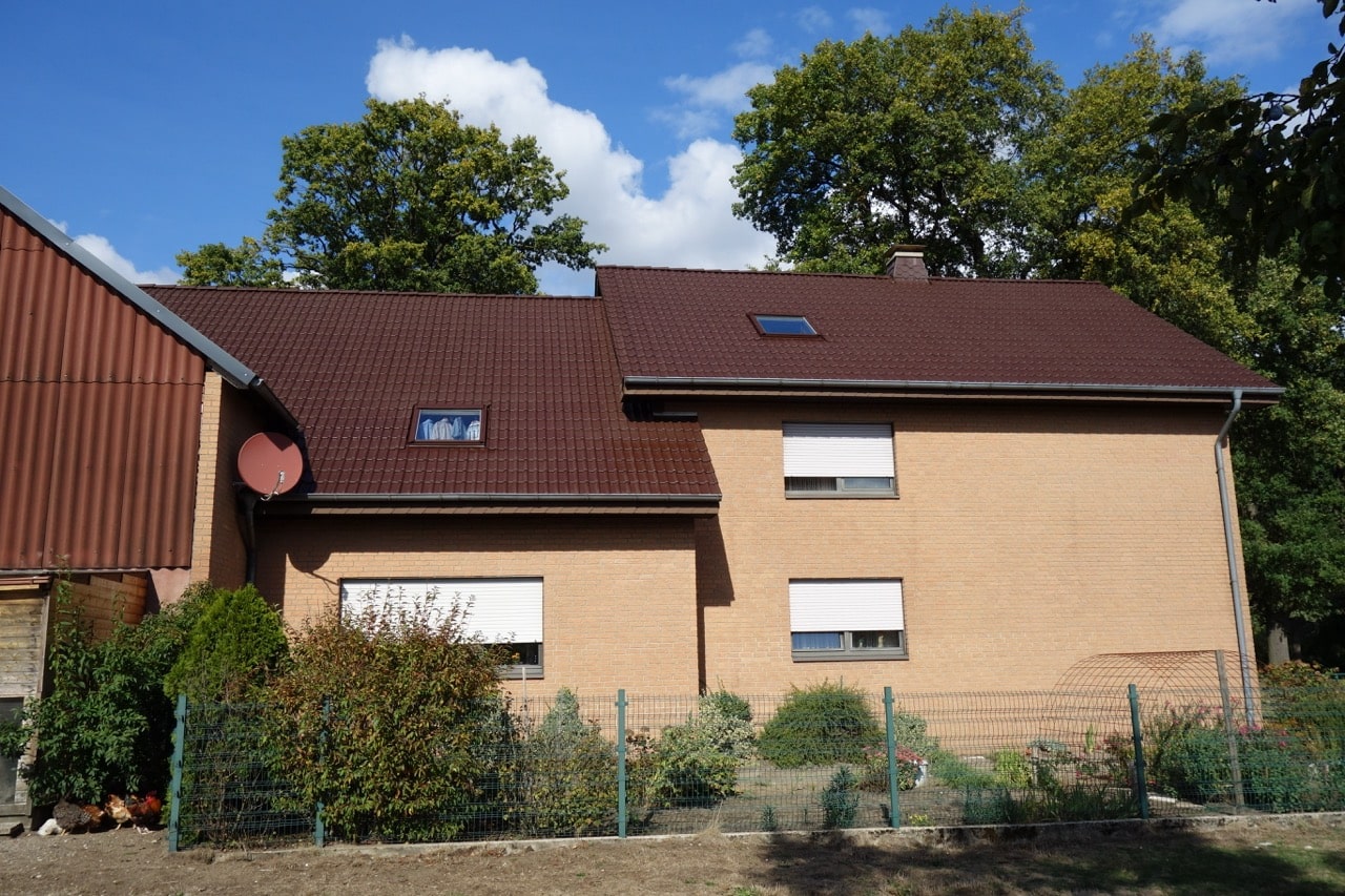 Außenansicht eines Hauses mit braunem Satteldach und Garten, renoviert von Bautenschutz Bogumil GmbH.