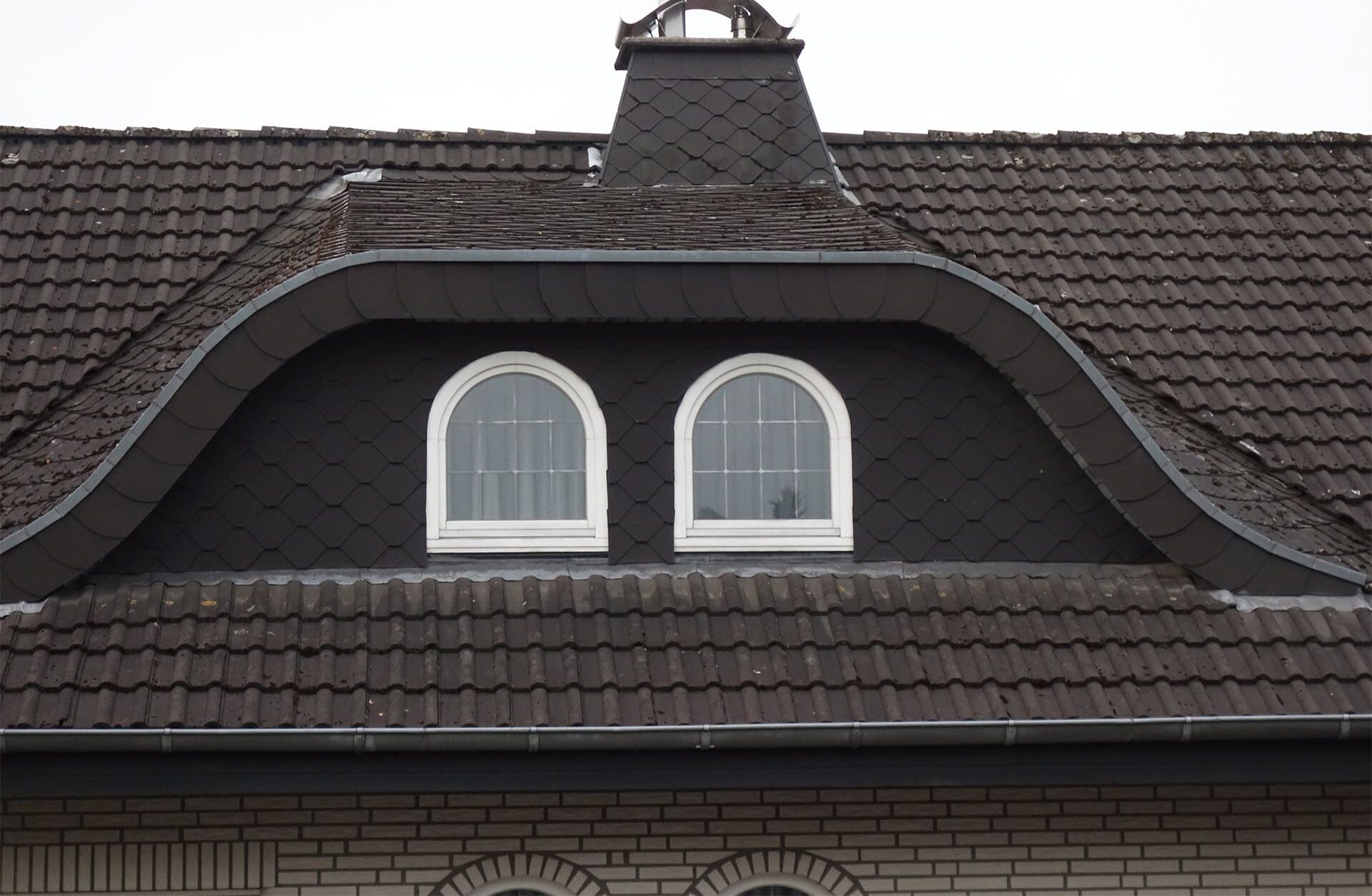 Dach mit zwei halbkreisförmigen Fenstern, gewartet von Bautenschutz Bogumil GmbH.