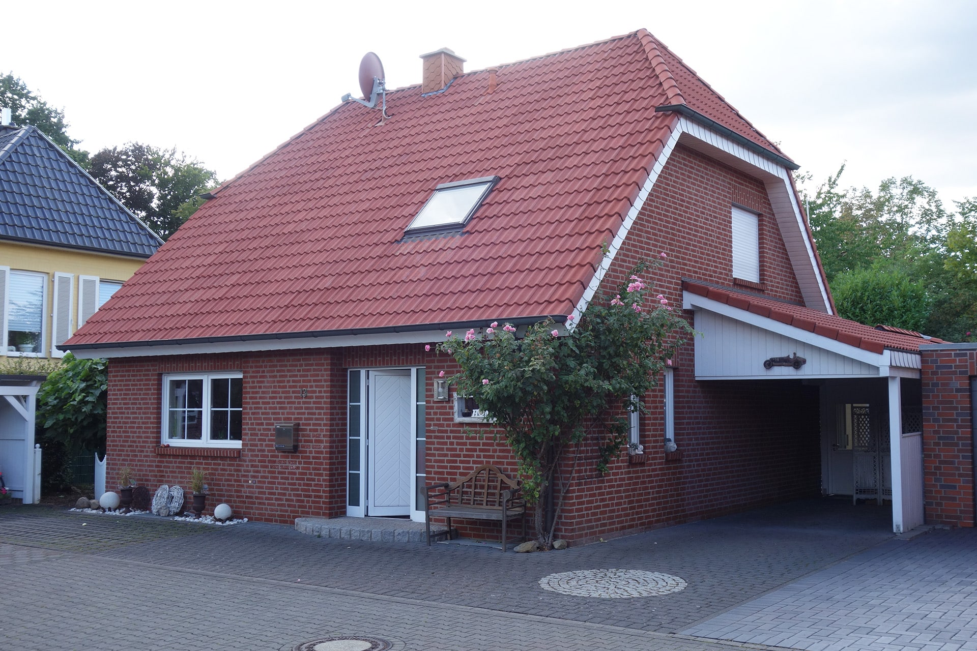 Ein Ziegelhaus mit rotem Dach und Garage, gepflegte Umgebung; Bauprojekt von Bautenschutz Bogumil GmbH.