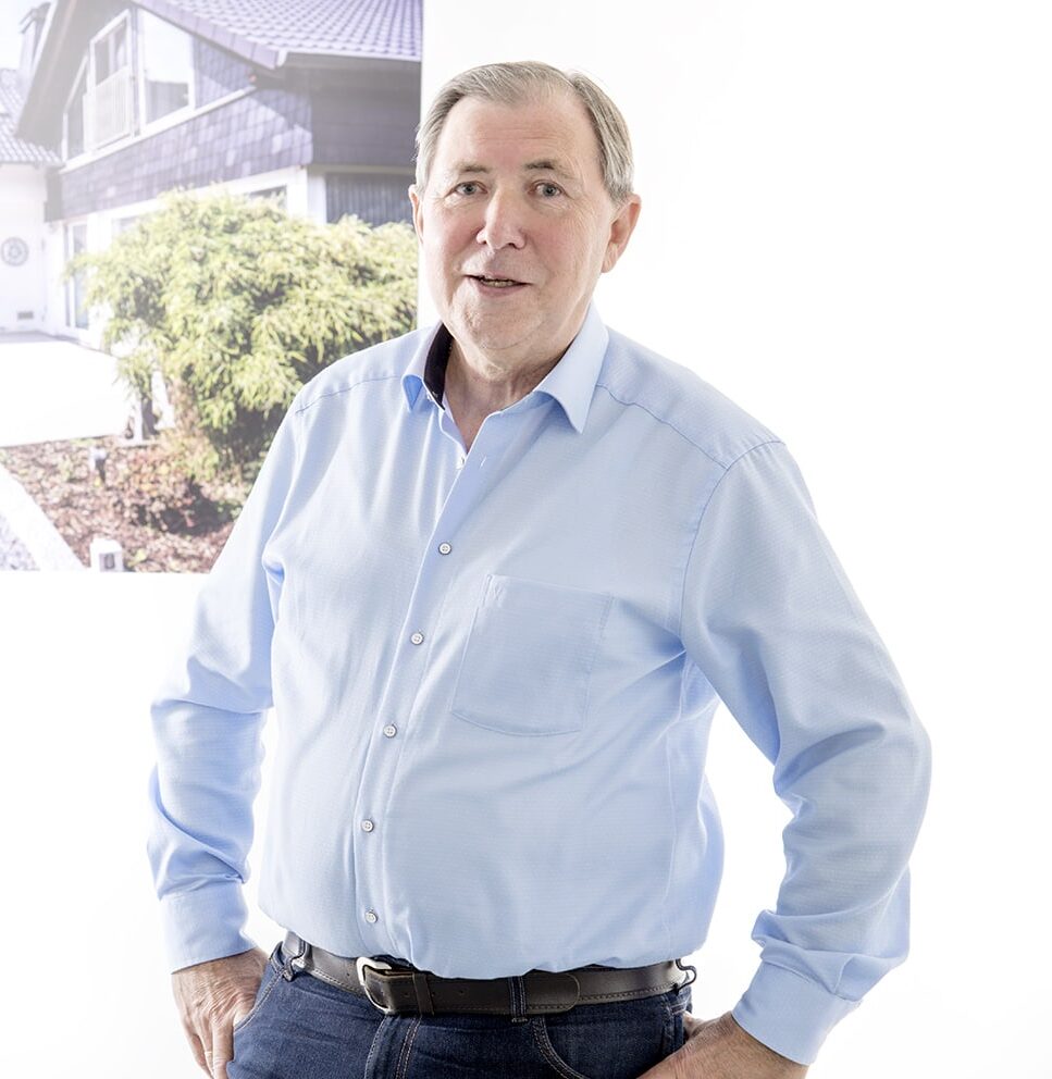 Mann im blauen Hemd steht vor einem Bild eines Hauses, verbunden mit Bautenschutz Bogumil GmbH.